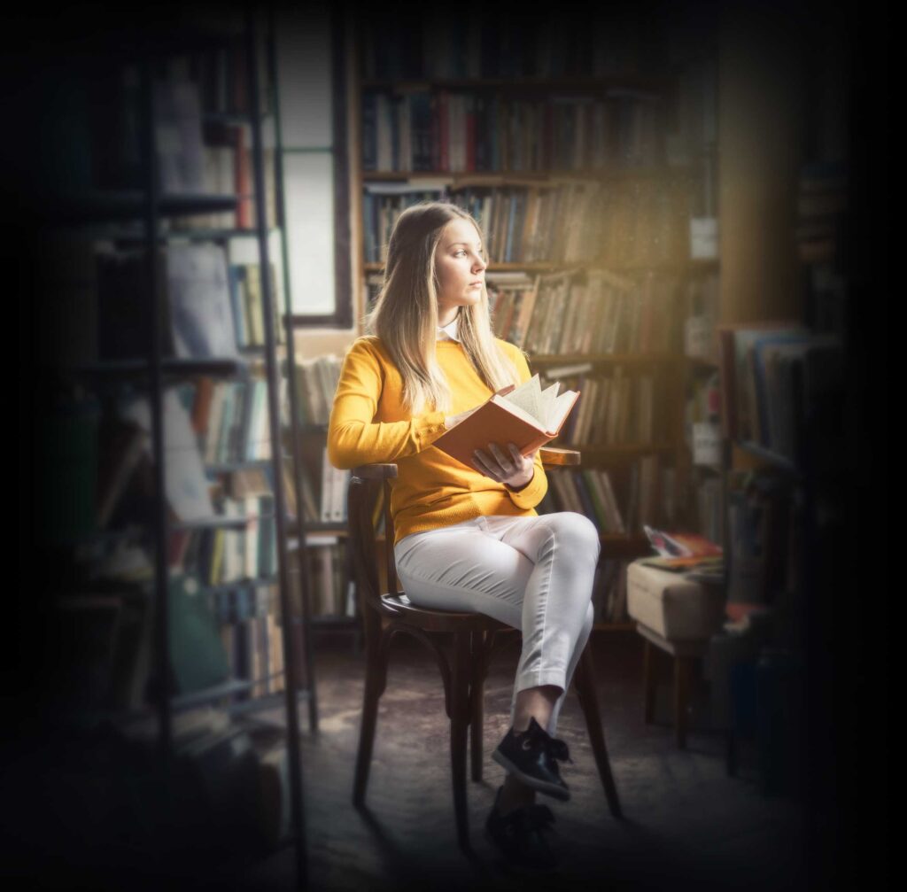 Women illuminated by sunlight while sitting in a library with an open book suggesting the power of leadership